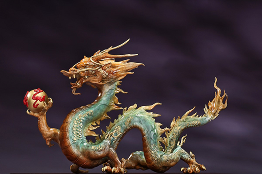 china dragon feng shui figurine holding a dragon pearl in green and gold on a dark background