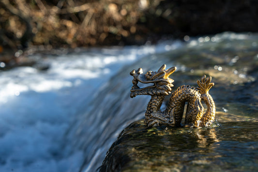 Golden Feng Shui brass dragon statue by a flowing waterfall for career and success luck