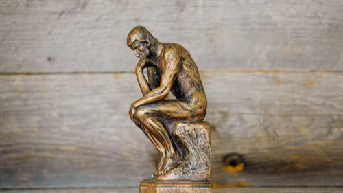 bronze thinker figurine on a wooden shelf, a calm symbol for a feng shui wealth corner