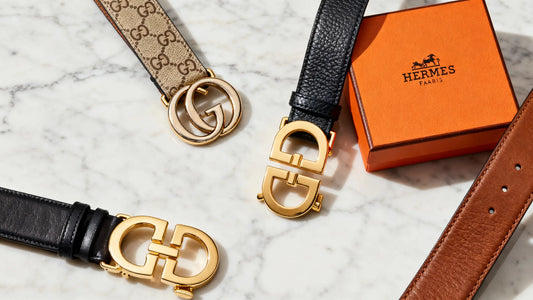 luxury designer belts from Gucci and Hermès displayed on marble surface representing iconic belt designers in fashion history