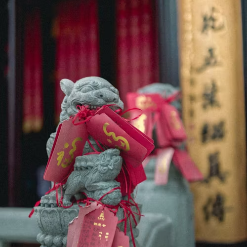 Stone lion statue adorned with red Feng Shui charms for luck and protection